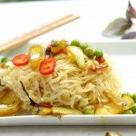 Asiatische Nudeln mit Erbsen, Zwiebeln, Peperoni, Curry, Kokosmilch und Thai-Basilikum