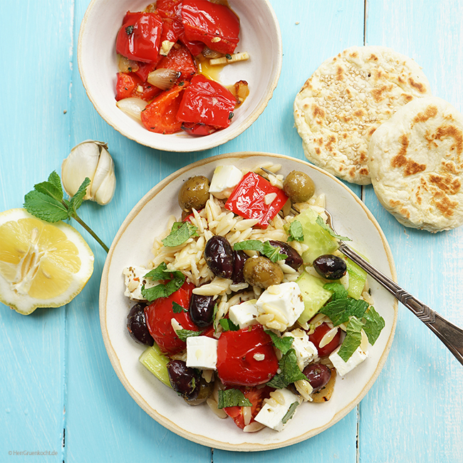 Griechischer Nudelsalat mit Kritharaki, geschmorter Paprika, Tomaten, Gurke, Feta, Oliven, frischer Minze und Sesam-Fladenbrot