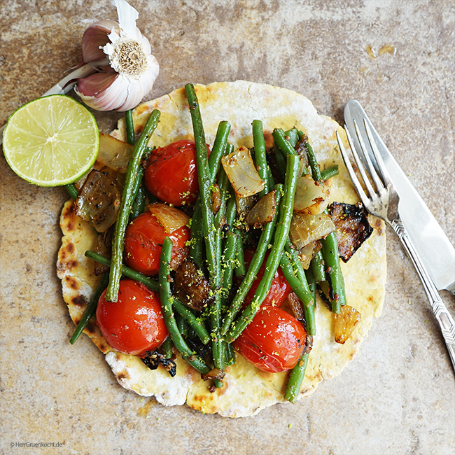 Kichererbsen-Kreuzkümmelfladen mit spicy geschmorten Zwiebeln, Knoblauch, Tomaten, grünen Bohnen und einem Hauch geriebener Limettenschale