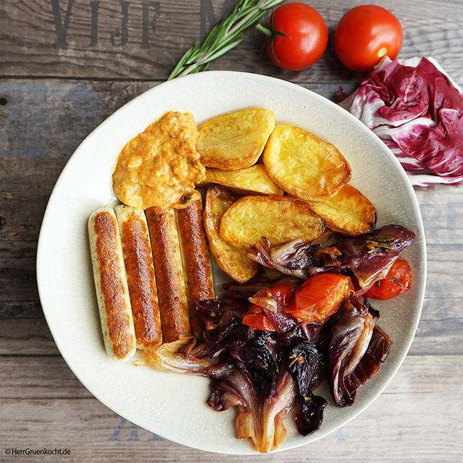 Geschmorter Radicchio, mit Tomaten, roten Zwiebeln, Backofenkartoffeln und vegetarischen Bratwürstchen