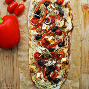 Spicy Pizza Matteo mit Tomaten, Paprika, Peperoni, Schafsfeta, Kalamatoliven und Zwiebeln