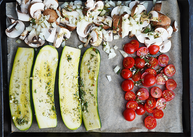 Überbackene Zucchini-Hälften mit Ofengemüse aus Pilzen, Tomaten und Zwiebel - mit einem Würzöl