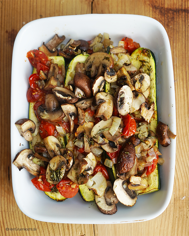 Überbackene Zucchini-Hälften mit Ofengemüse aus Pilzen, Tomaten und Zwiebel - mit einem Würzöl